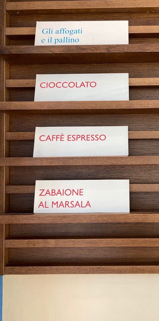 Handwritten wooden flavour tags on a rack — affogati, cioccolato, caffe espresso, zabaione al Marsala