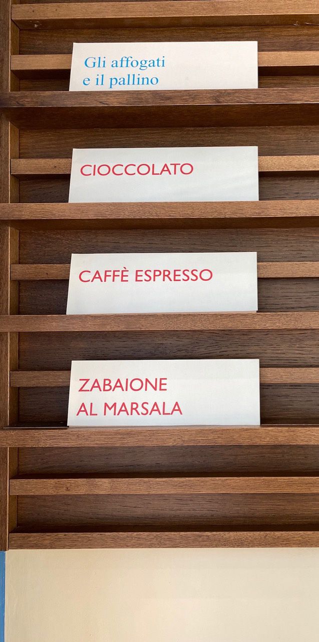 Handwritten wooden flavour tags on a rack — affogati, cioccolato, caffe espresso, zabaione al Marsala