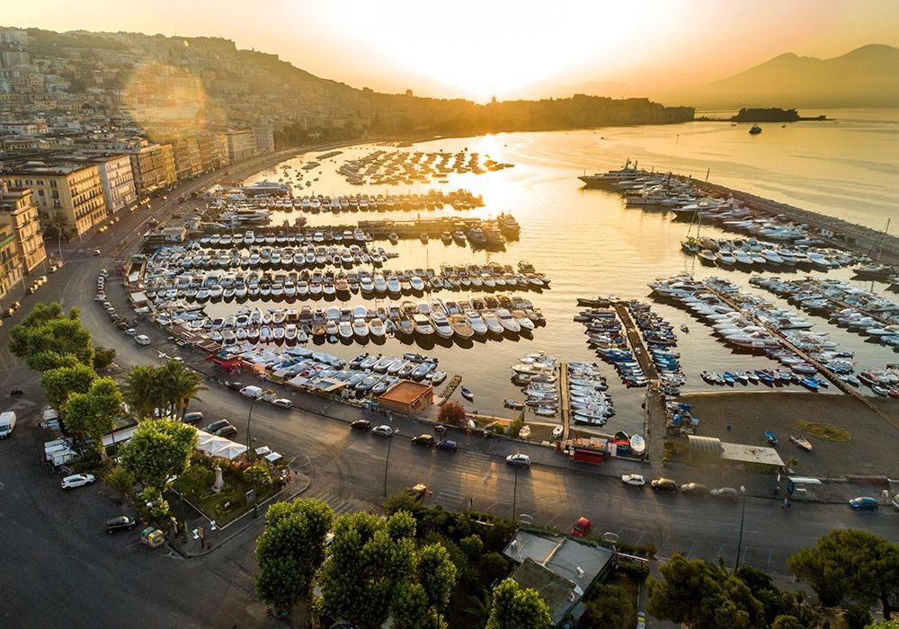 The Mergellina marina at sunset from above, boats packed into rows along the Naples seafront