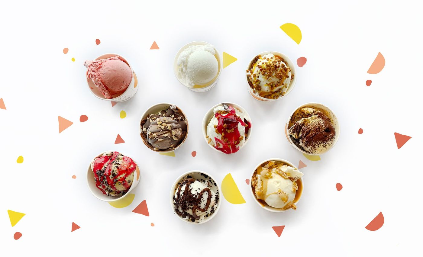 Nine cups of gelato photographed from above on a white ground, each with a different topping