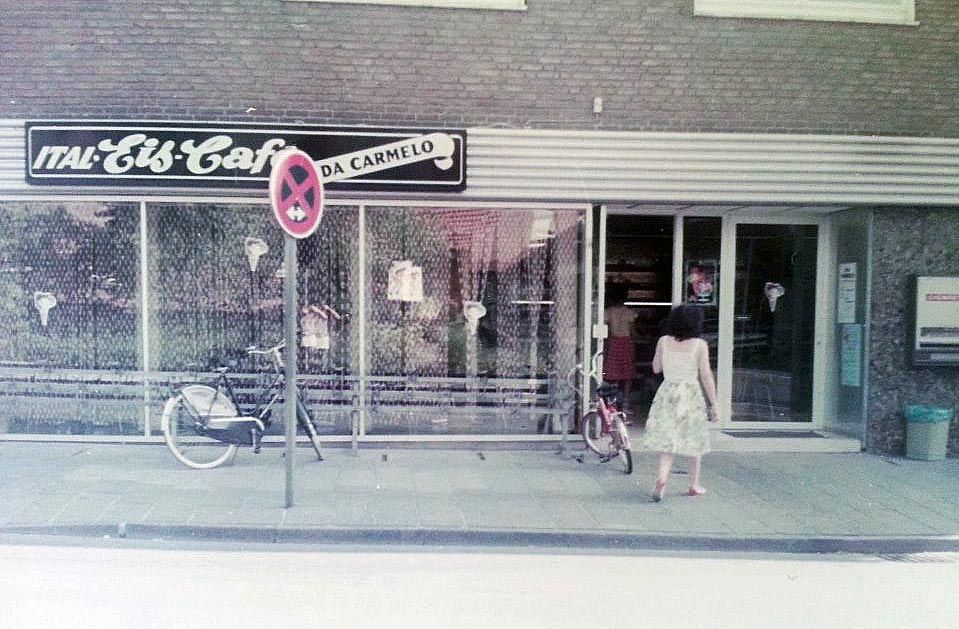 A faded street photograph of the Eis-Cafe shopfront with a bicycle parked outside