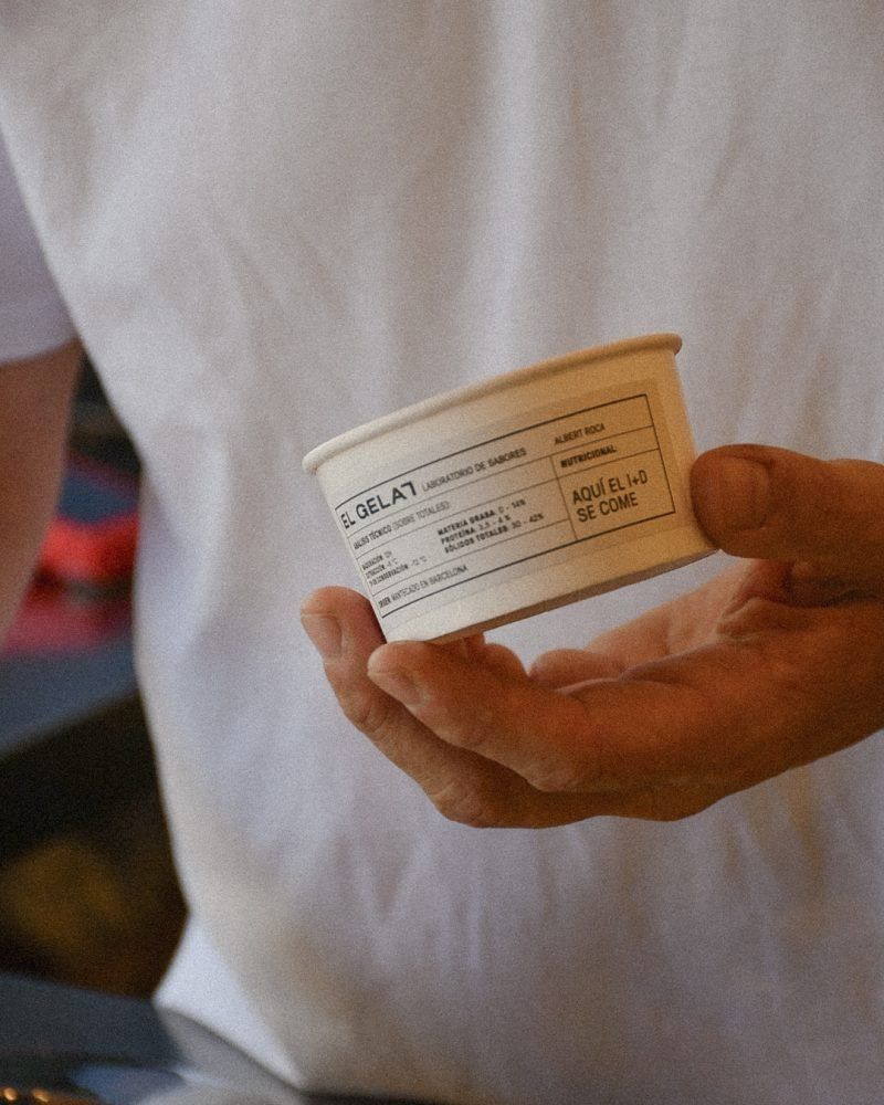 Two hands holding a tub of gelato, turned so the ingredient label on the side faces the camera