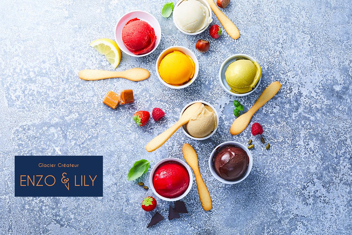 Small bowls of brightly coloured sorbet and ice cream arranged with fruit and biscuits on stone