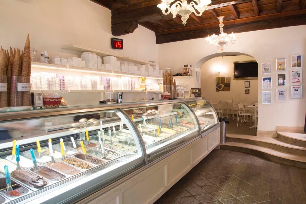 The shop interior, a long chilled case of gelato under a chandelier, with framed prints on the far wall
