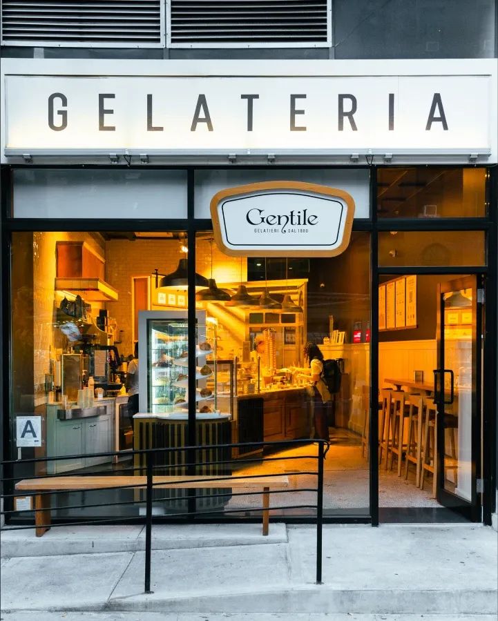 The Gentile shopfront at night, warm light spilling from the window onto the pavement