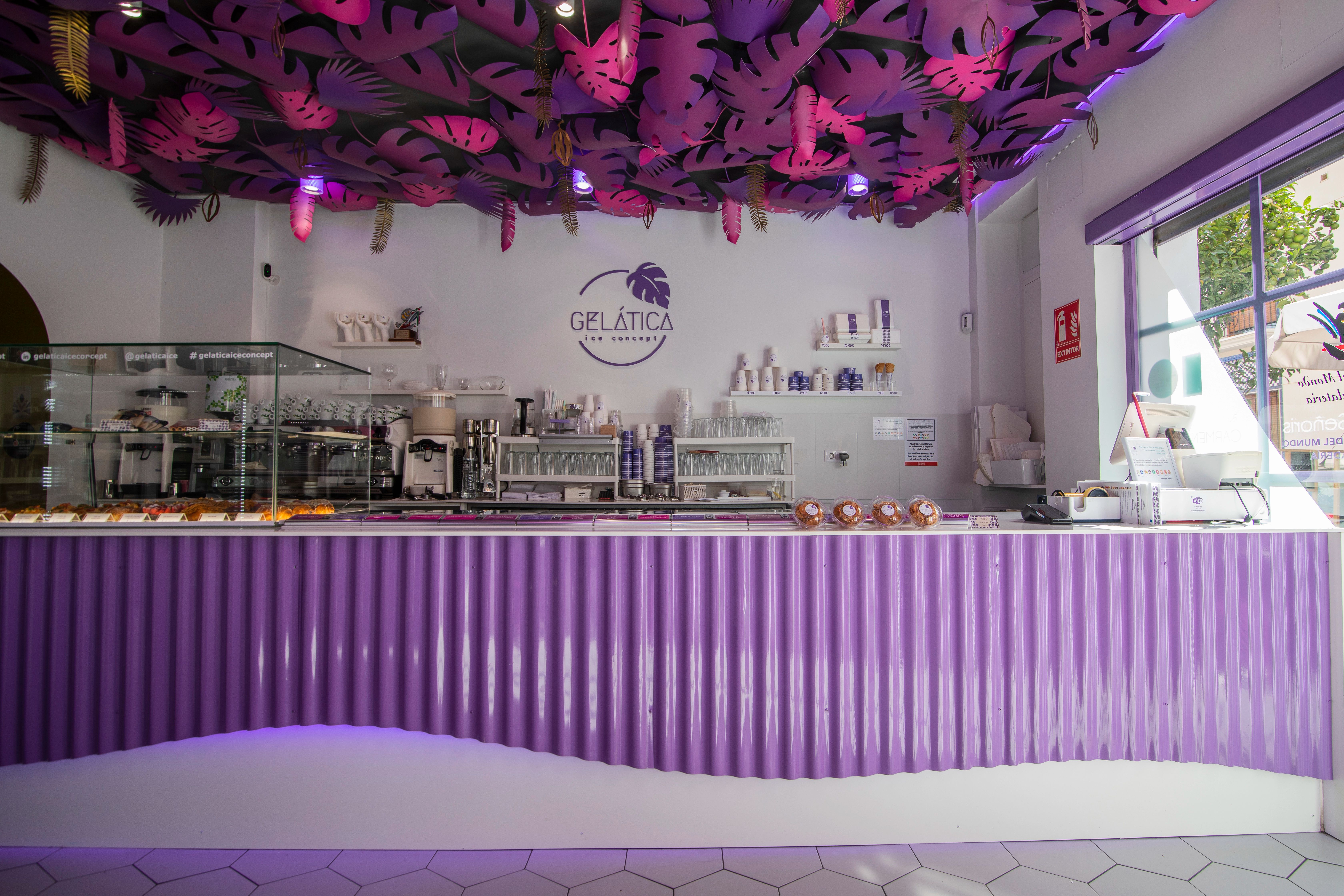 The shop interior under purple light, the counter running the length of the room