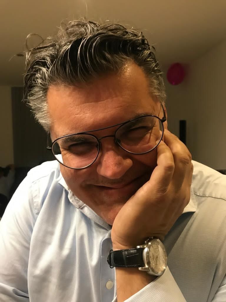 A portrait of the maker in glasses, head resting on one hand