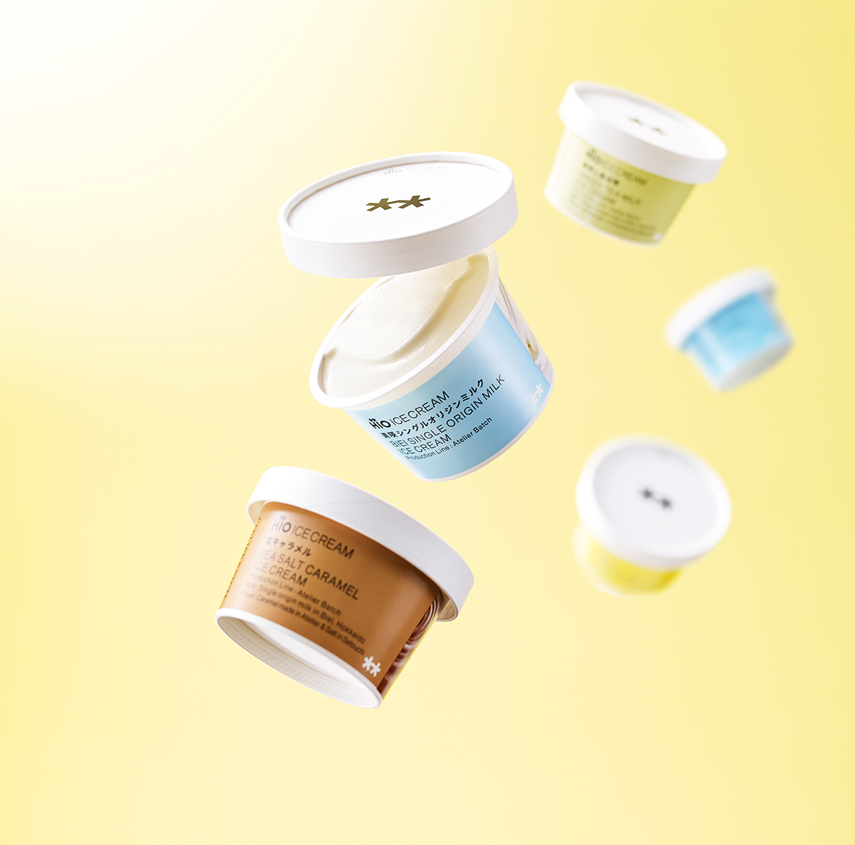 Lidded tubs of ice cream floating against a yellow ground