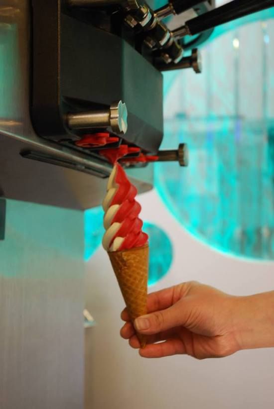 A red and white soft-serve swirl being drawn from the machine into a cone