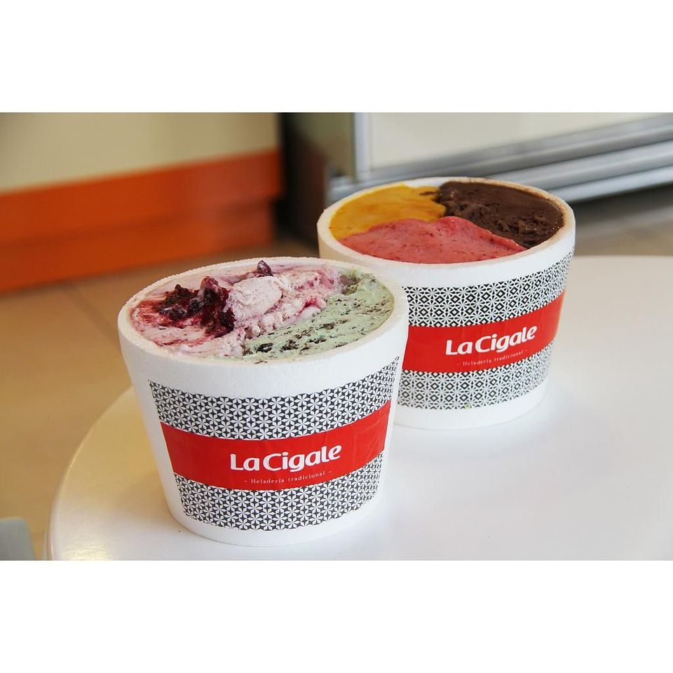 Two La Cigale tubs side by side on a counter, one filled with pistachio and berry, one with three flavours