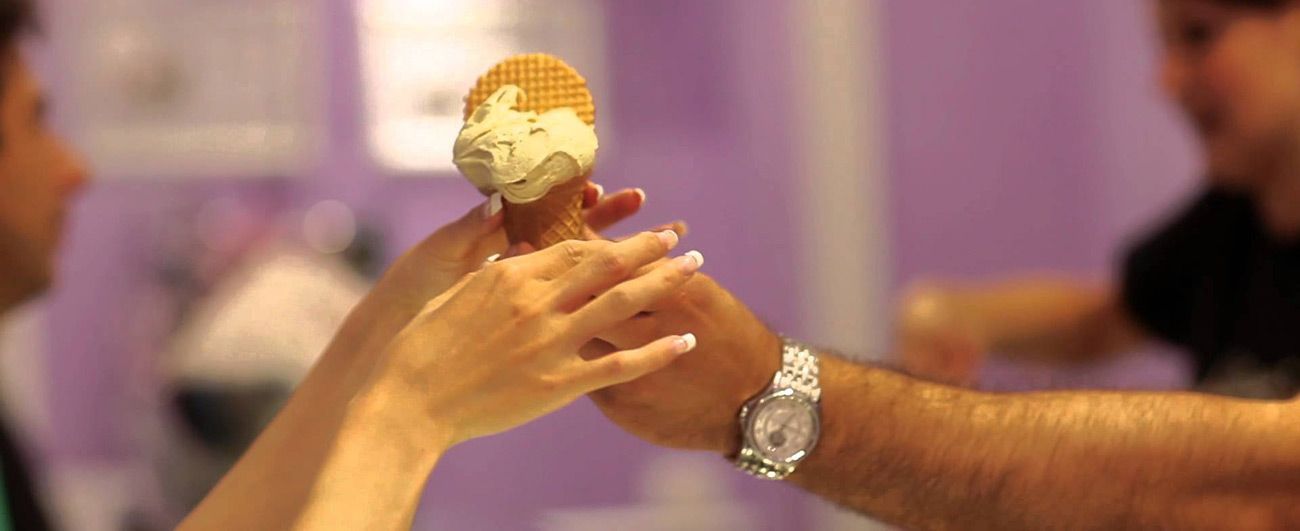 A cone being passed across the counter from one hand to another