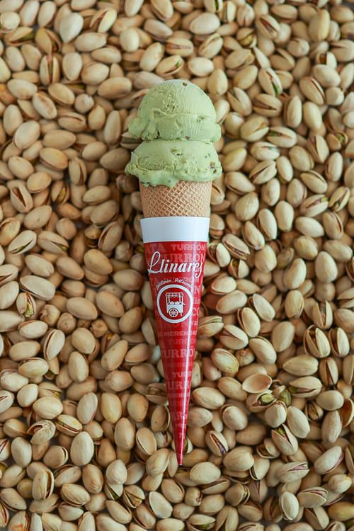 A pistachio cone standing upright in a bed of shelled pistachios