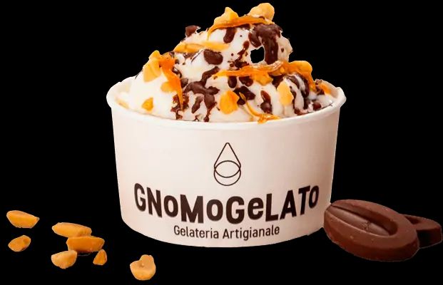 A tub of gelato under sauce and toppings on a green ground