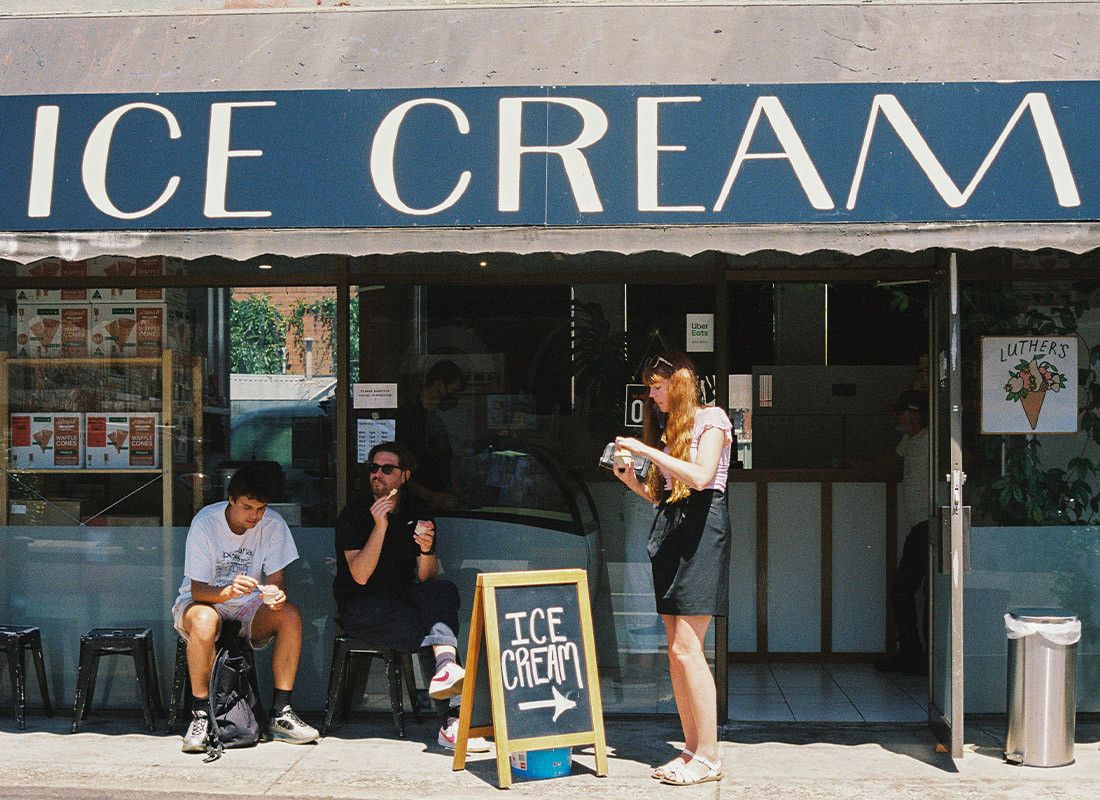 People sitting outside the shopfront under a painted ICE CREAM sign