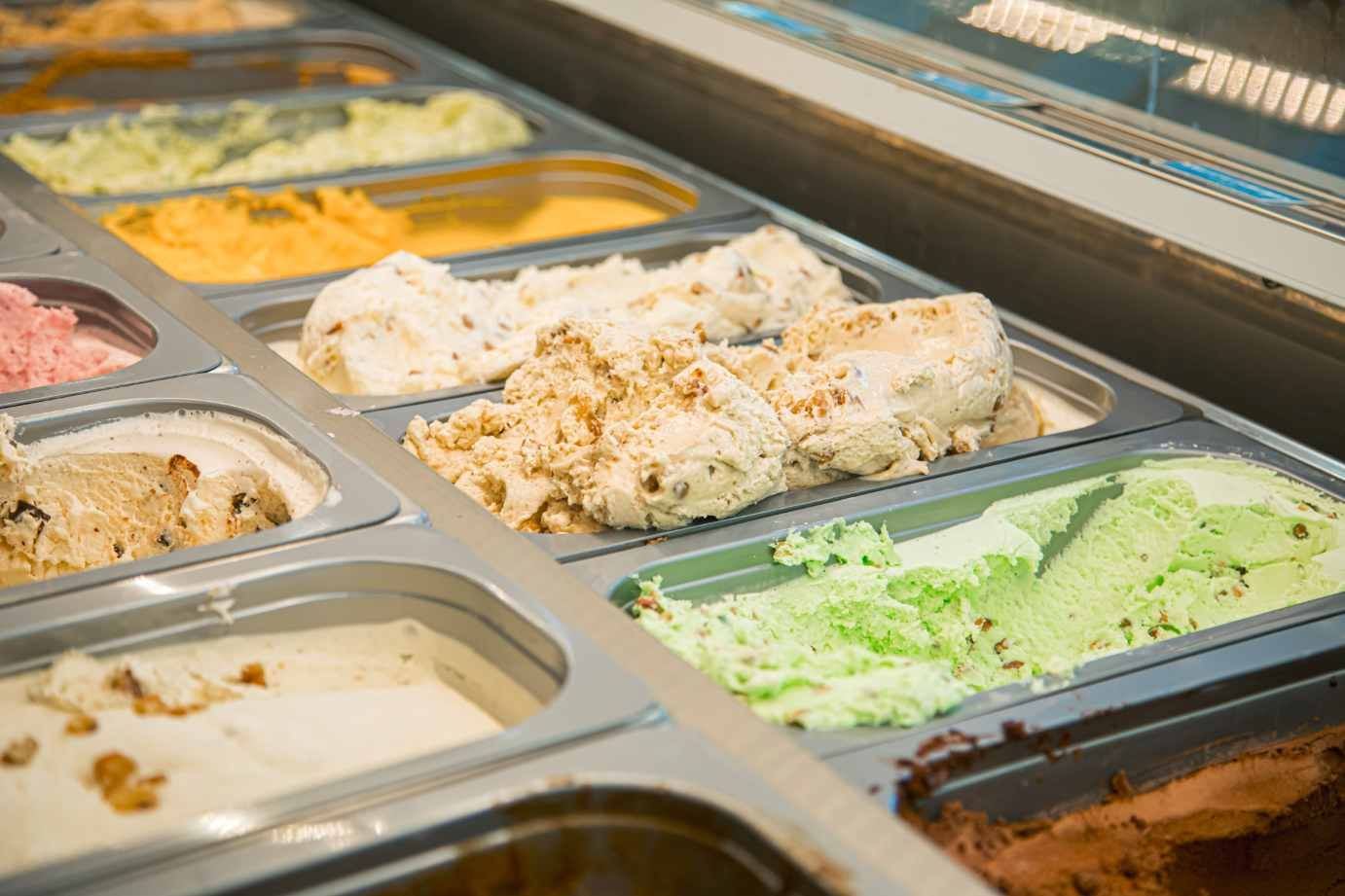 A display case of open tubs, pale green and cream and nut-flecked