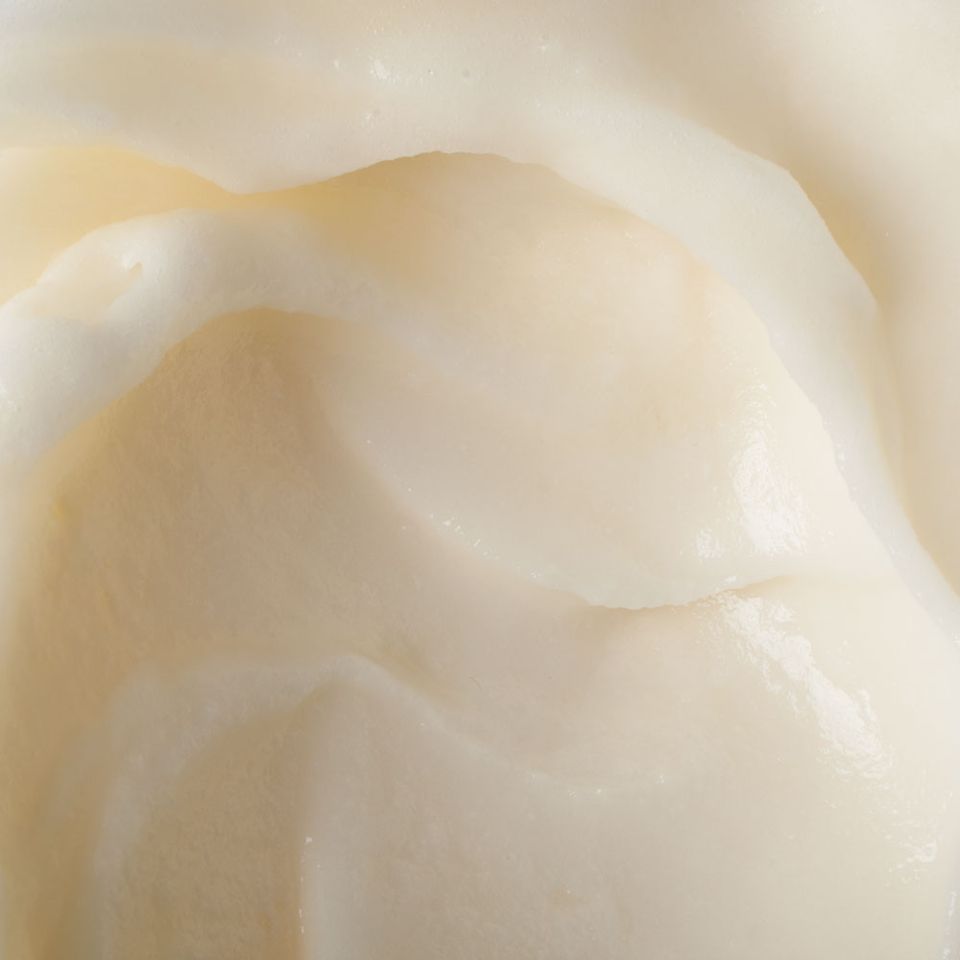 An extreme close-up of the folded surface of pale ivory sorbet, filling the frame