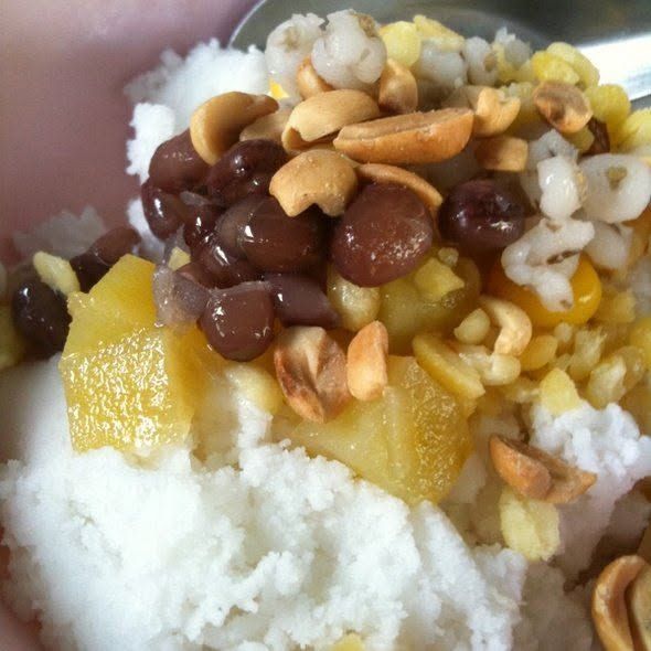 A bowl of coconut ice cream heaped with red beans, roasted peanuts, jackfruit, sweetcorn and barley