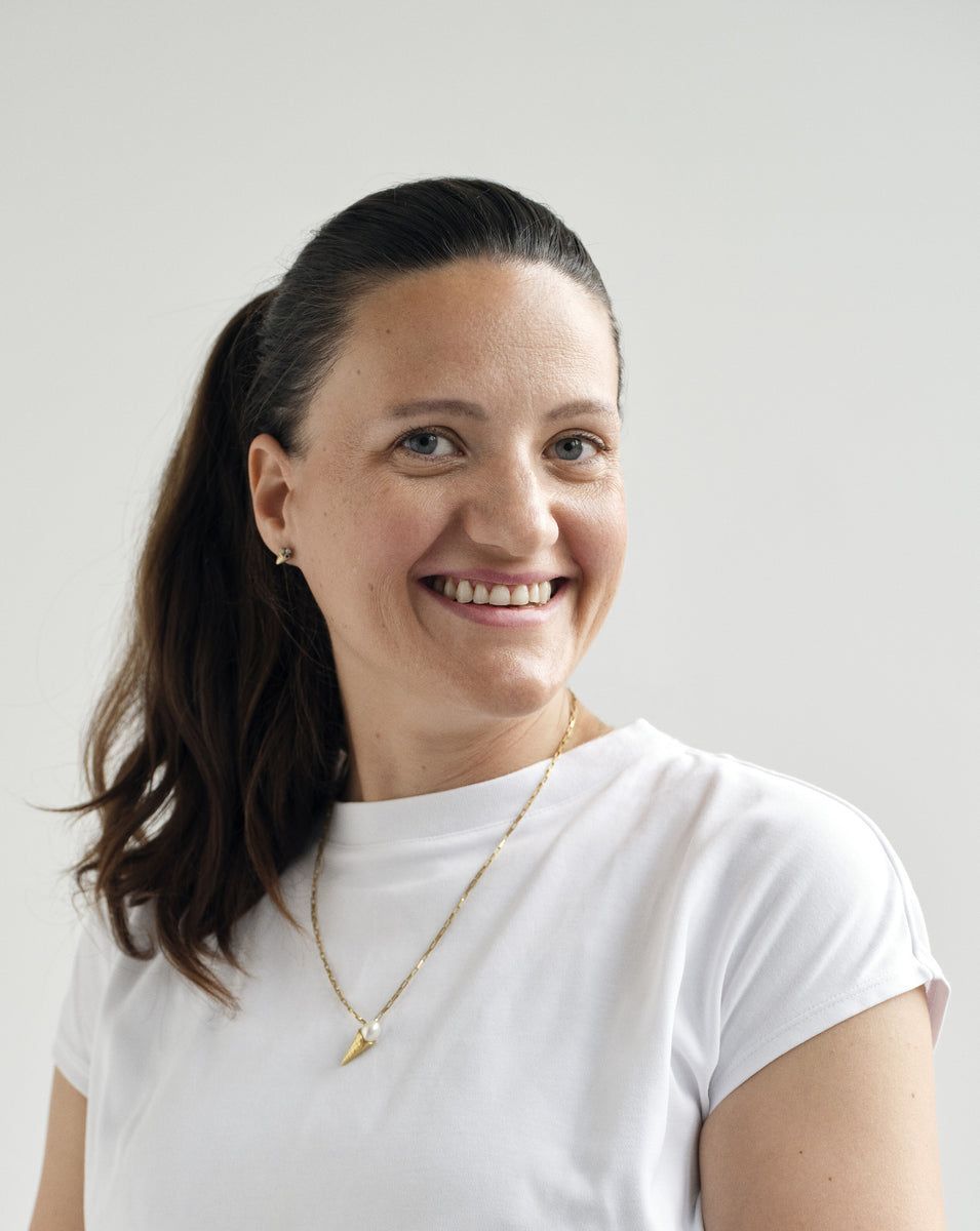 A portrait of the maker in a white T-shirt, laughing, against a pale wall