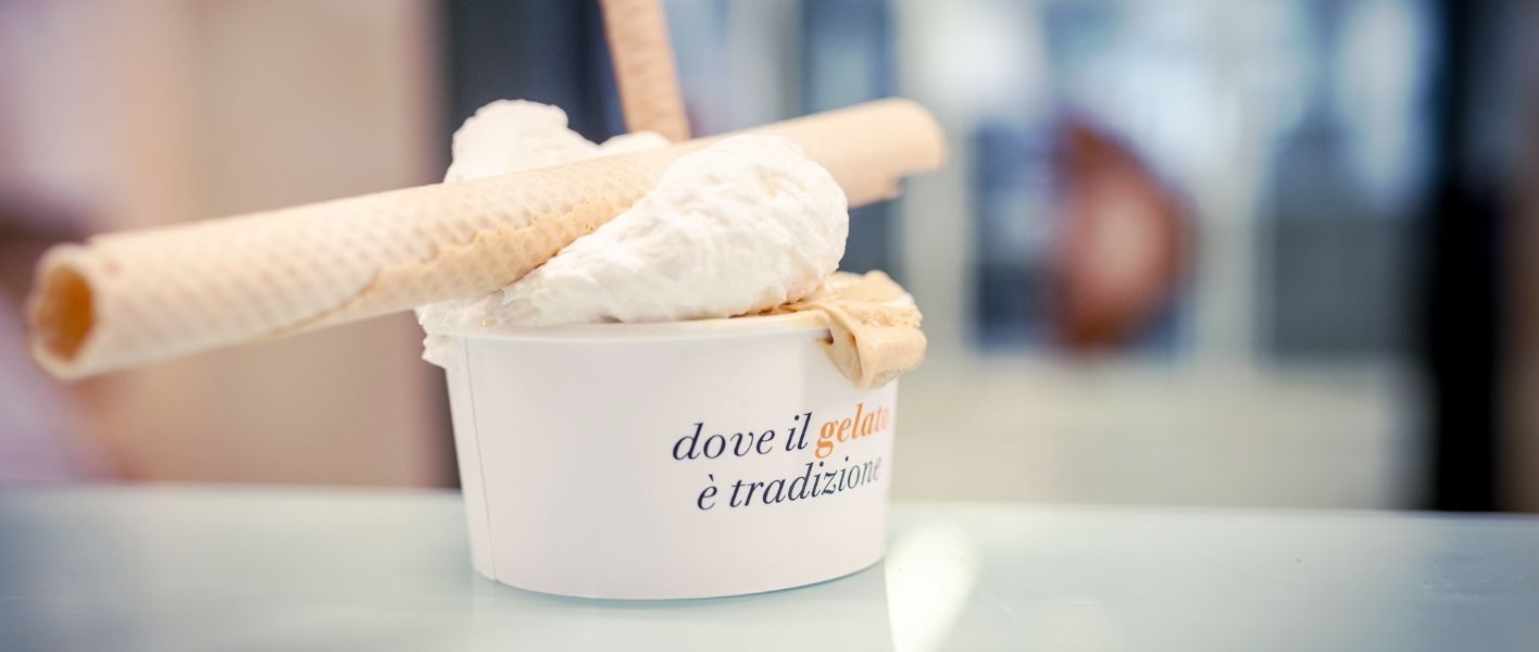A paper cup of gelato finished with rolled wafers