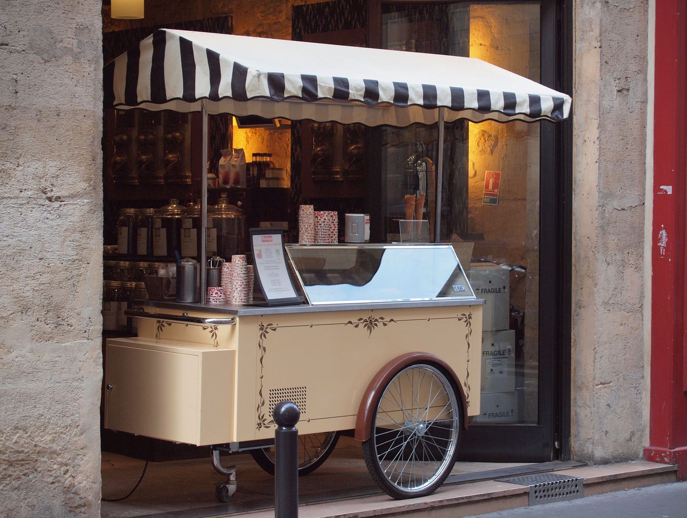 A small ice-cream cart under a striped awning on a Paris street