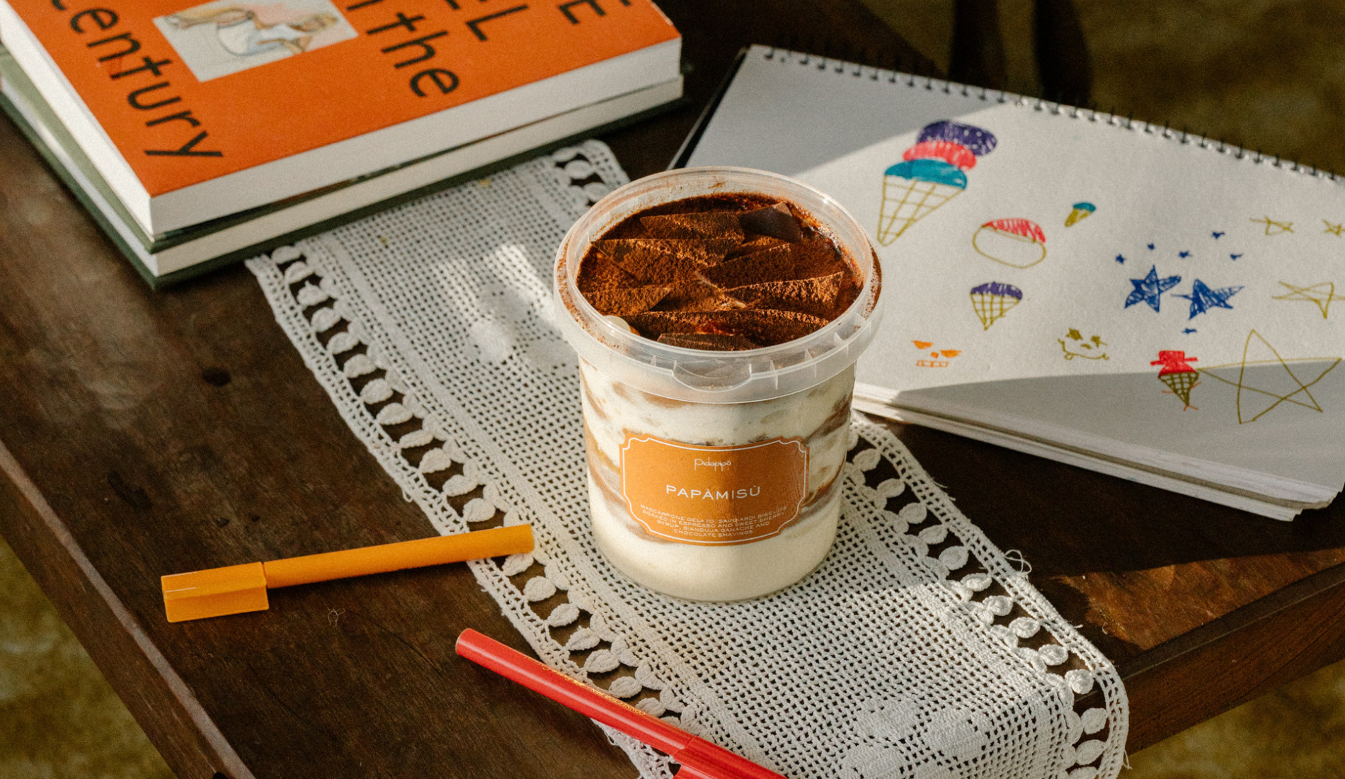 A cup of gelato set down on books and paper on a desk