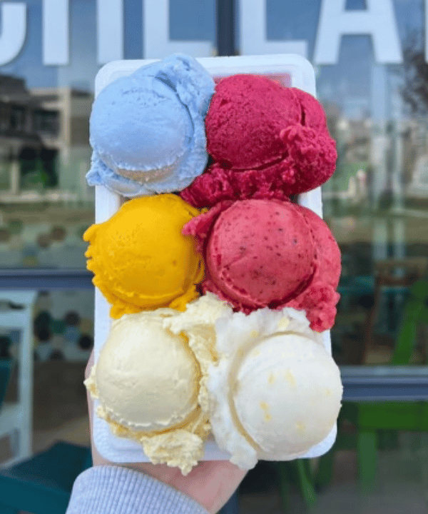 A hand holding a cone stacked with five scoops in different colours