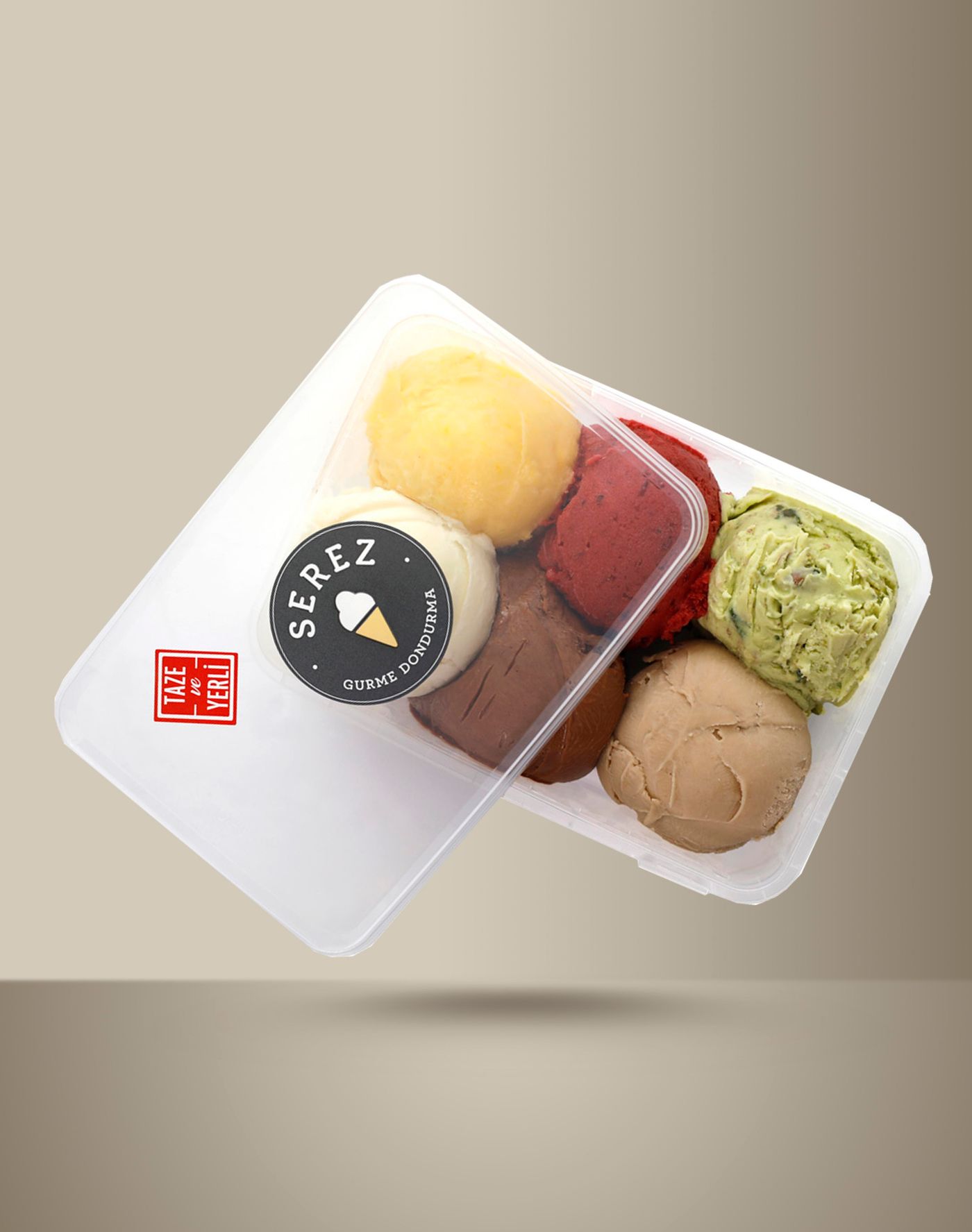 A clear tub of Serez ice cream tilts with its lid ajar, showing six scoops — pale yellow, white, deep red, chocolate, pistachio green flecked with nuts, and tan — under a black SEREZ GURME DONDURMA roundel and a red TAZE ve YERLİ stamp
