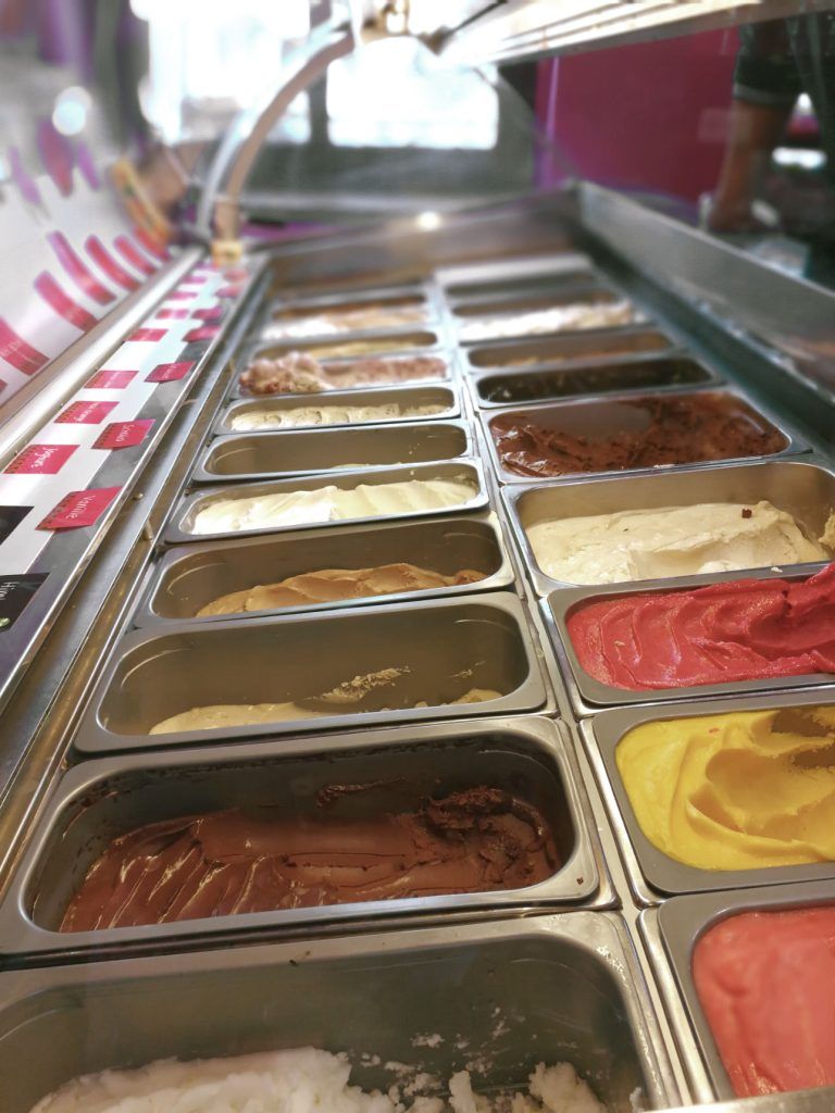 A long display case of gelato tubs seen down its length