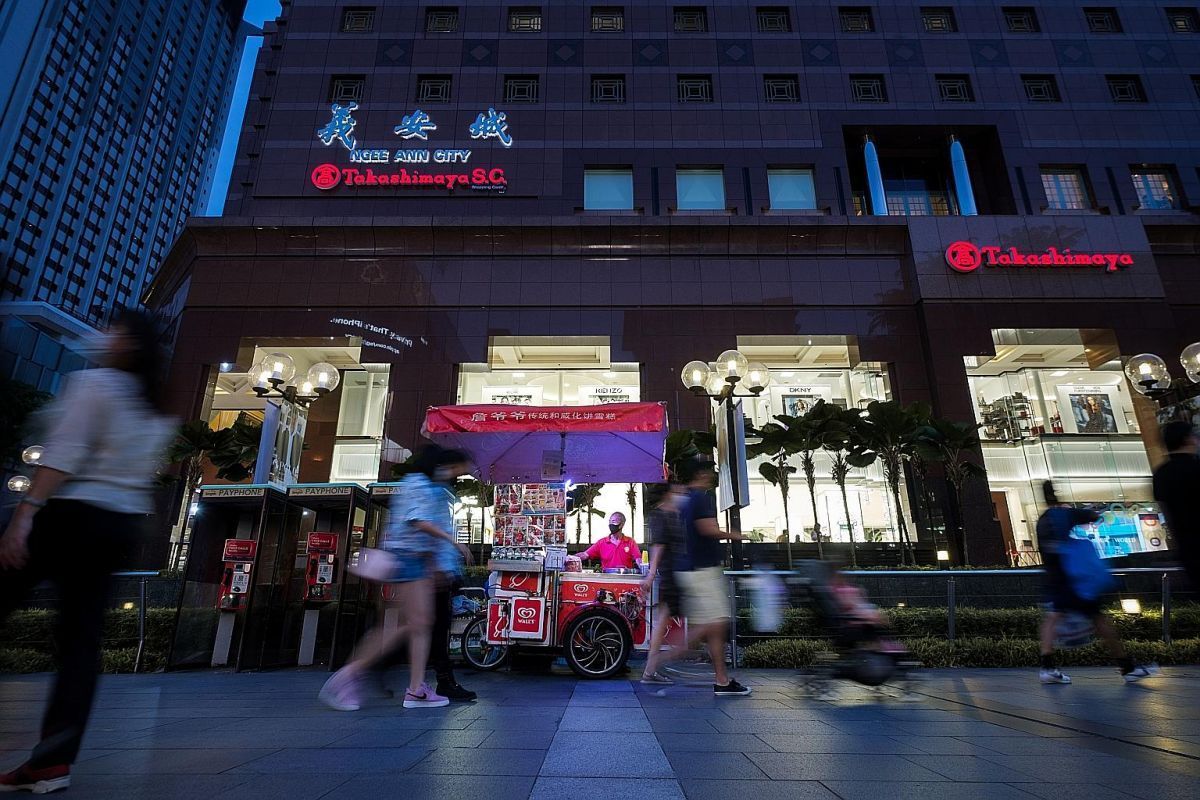 The ice-cream cart parked at night on Orchard Road outside Ngee Ann City, passers-by blurred around it