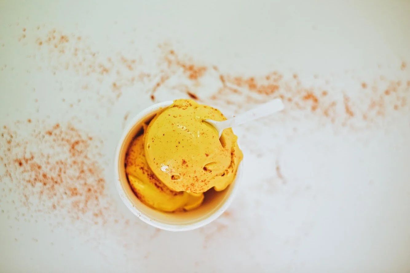 A cup holding a single orange scoop, dusted around the rim