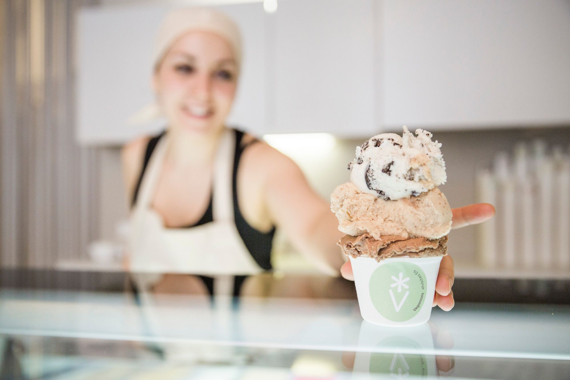 A member of staff handing a cup of ice cream across the counter