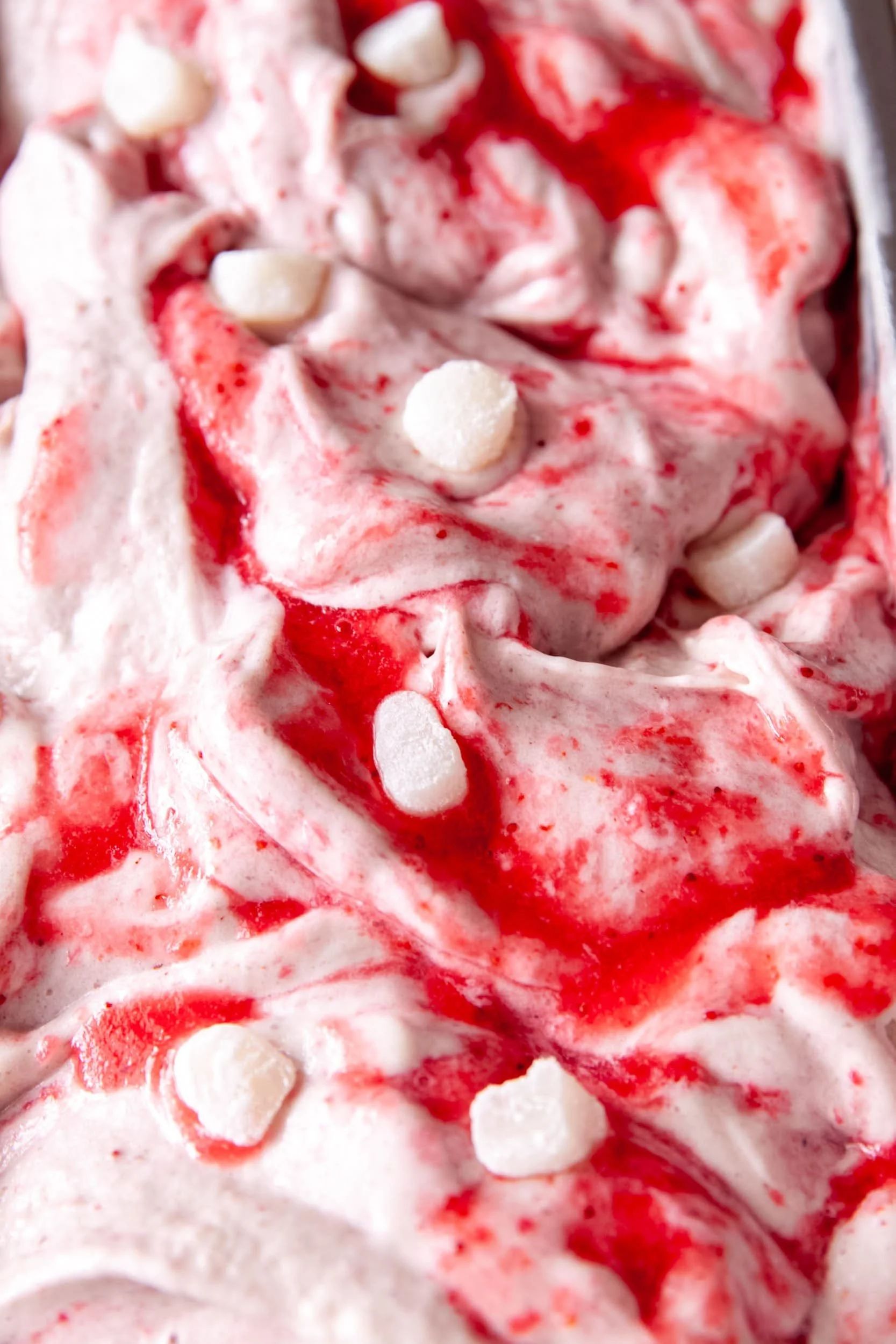 A close crop of strawberry ice cream rippled with fruit and set with marshmallows